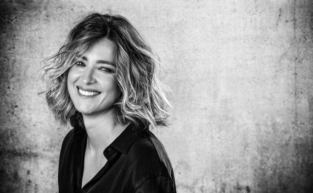 Sandra Barneda, autora, sonríe ante cámara en retrato en blanco y negro con fondo texturizado