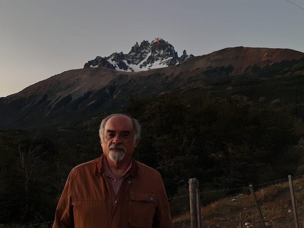 Juan Mihovilovich frente a montaña nevada al atardecer, retrato en ambiente rural