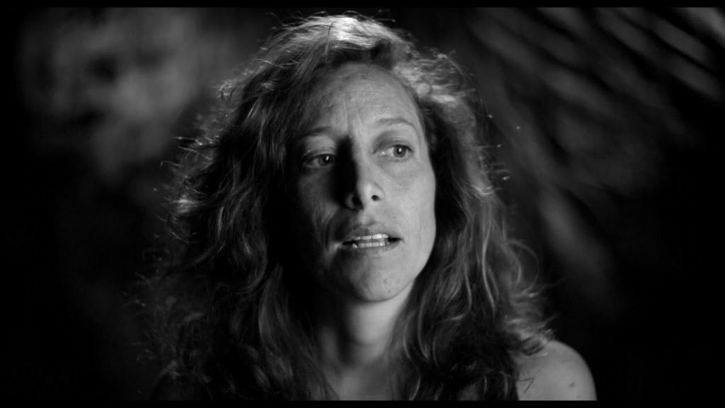 Mujer de cabello largo y ondulado mirando hacia arriba, fotografía en blanco y negro con iluminación dramática