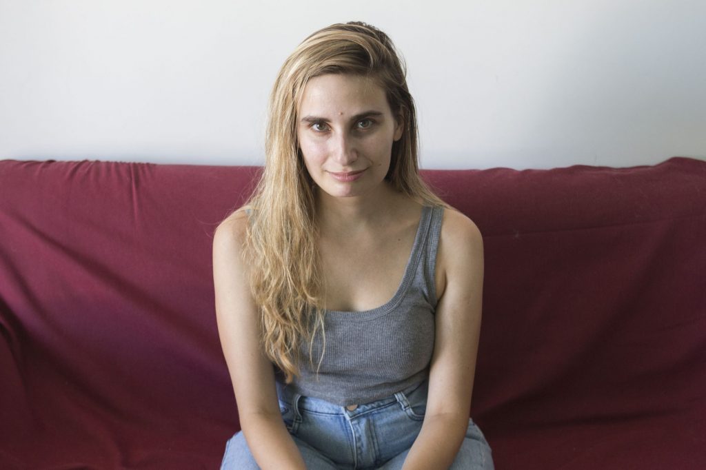 Tamara Tenenbaum, escritora y periodista argentina, sentada en un sofá granate frente a la cámara