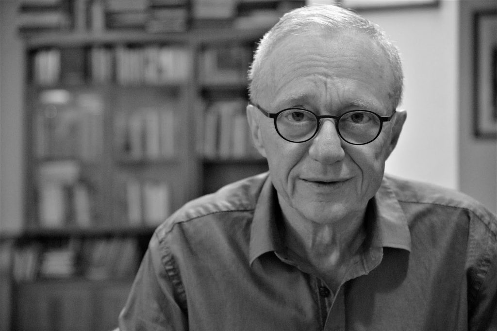 David Grossman, escritor israelí de cabello blanco y gafas, retratado en blanco y negro frente a estantería con libros