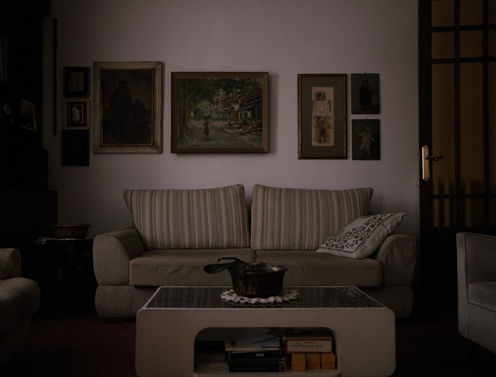 Sala de estar minimalista con sofá gris a rayas, cuadros abstractos en la pared y mesa de centro moderna