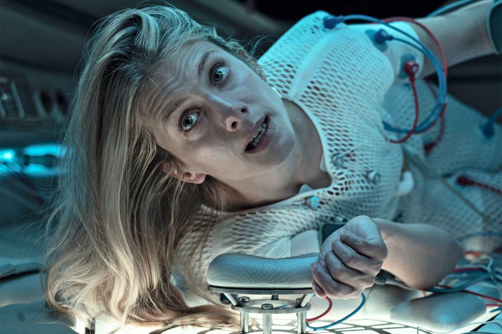 Mélanie Laurent en traje espacial dentro de una nave, con cabello largo flotante y expresión de asombro en ambiente