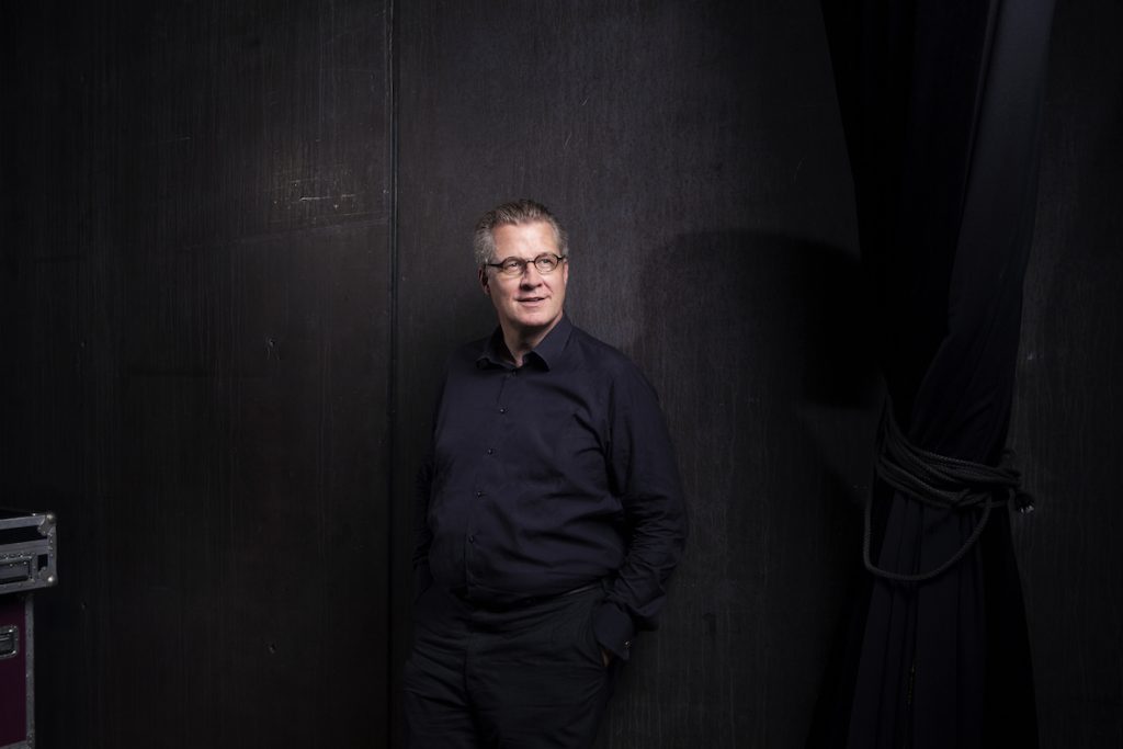 Philipp Blom, historiador y escritor austríaco, de pie frente a fondo oscuro con gafas y camisa negra