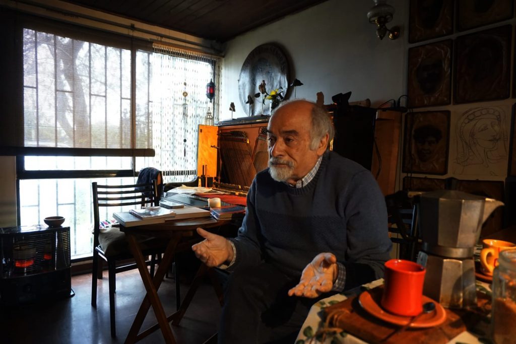 Juan Mihovilovich en su estudio rodeado de libros, escritorio y objetos personales, trabajando en su escritorio