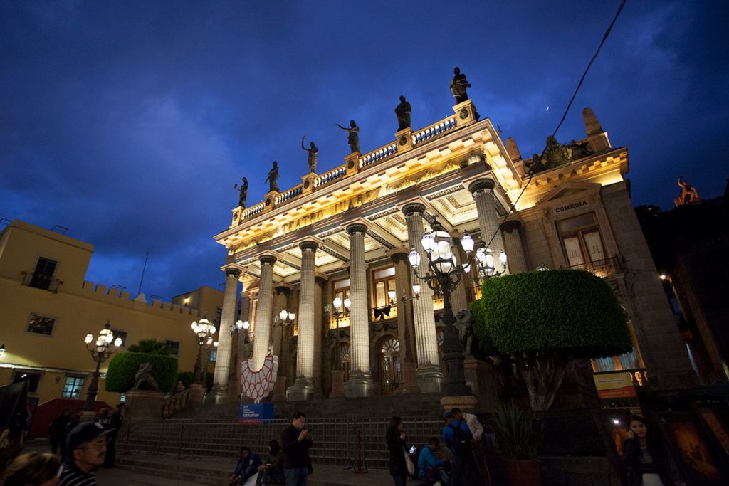 Teatro Juárez iluminado al atardecer en Guanajuato, con fachada neoclásica, columnas doradas y cúpula decorada