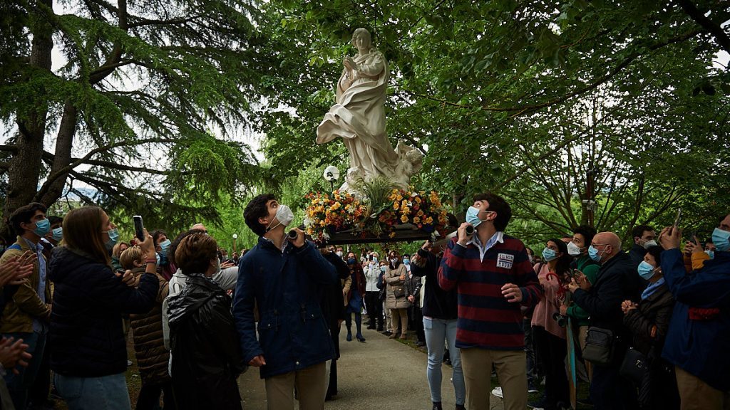 Grupo de personas reunidas alrededor de una estatua de la Virgen de Éfeso bajo dosel de árboles