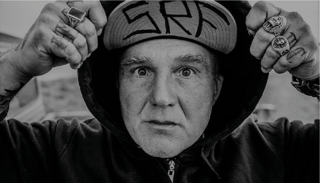 Hombre mayor con gorra negra ajustada en la cabeza, expresión seria, fotografía en blanco y negro, estilo