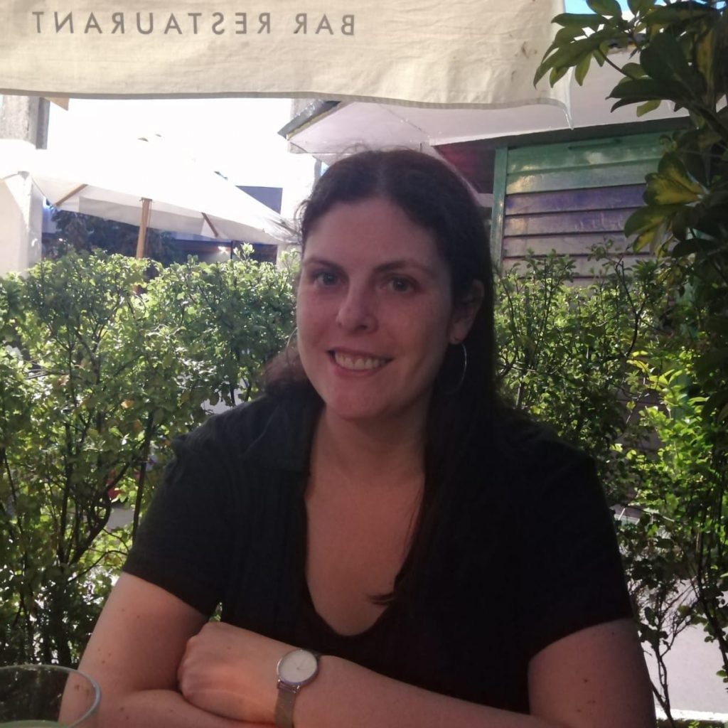 Francisca Gaete, escritora, sonríe a la cámara en un espacio exterior con vegetación de fondo
