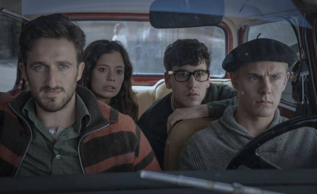 Cuatro personajes en el interior de un vehículo: tres hombres y una mujer, con expresiones tensas en escena de serie