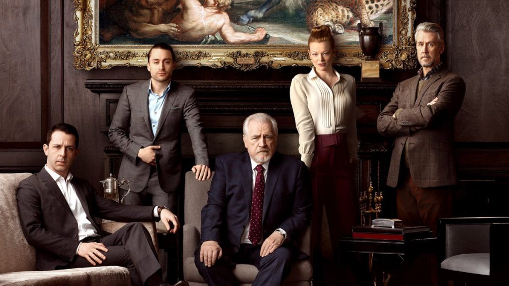 Seis hombres en traje posando en una sala lujosa con cuadro al fondo, escena de la serie Succession