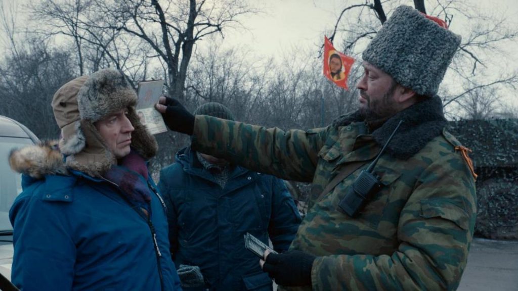 Soldado en uniforme militar interroga a dos civiles en la nieve durante conflicto armado en Donbass