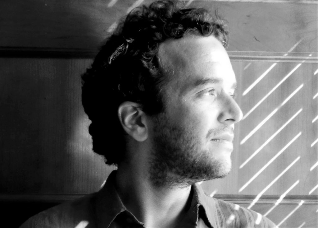 Retrato en blanco y negro de perfil de Enrique Winter, escritor, contra fondo con líneas geométricas