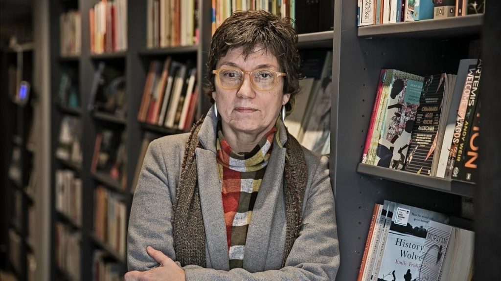 Antònia Carré-Pons en biblioteca rodeada de libros, con gafas y expresión reflexiva