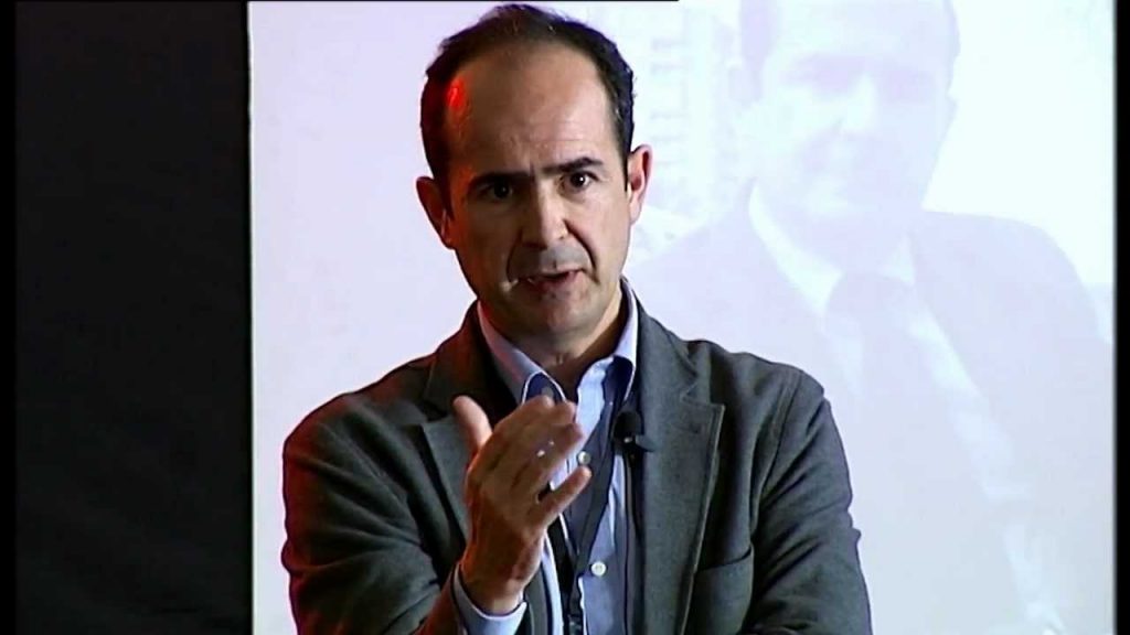 Higinio Marín, hombre de mediana edad con gafas, durante una presentación o conferencia, gesticuleando mientras habla