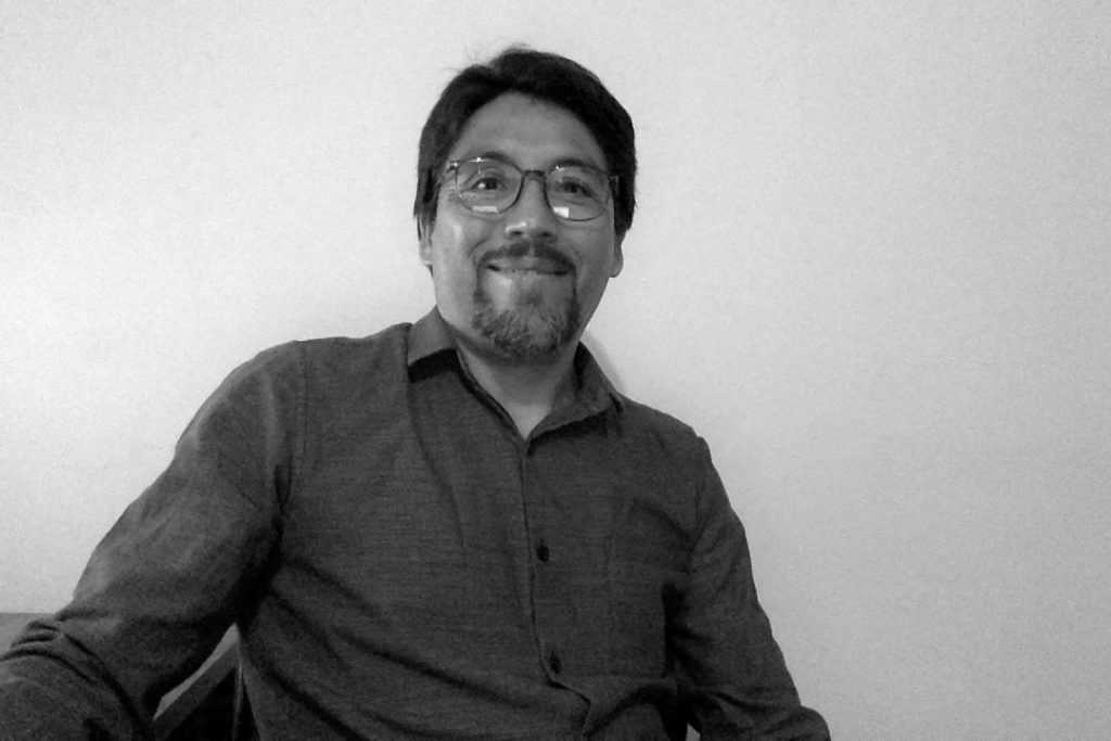 Cristián Oyarzo, hombre con lentes y camisa oscura, retrato en blanco y negro