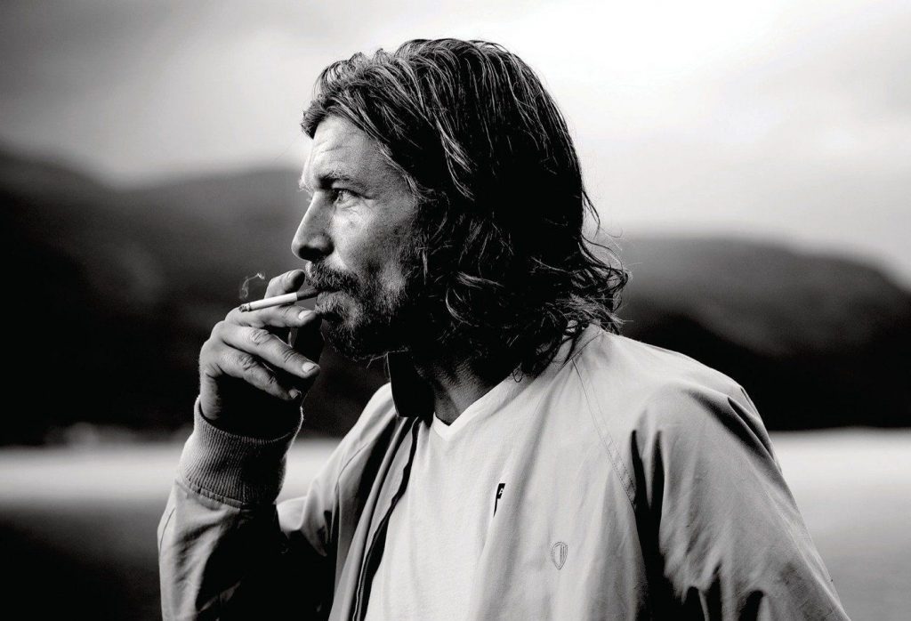 Karl Ove Knausgård en retrato blanco y negro, de perfil, con la mano cerca del rostro en actitud contemplativa frente