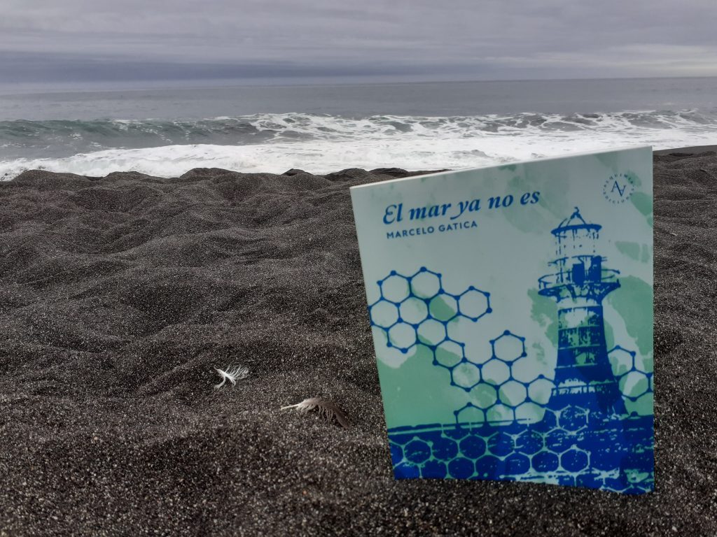 Cartel con frase "El mar ya no es" y lighthouse en playa rocosa con olas de fondo