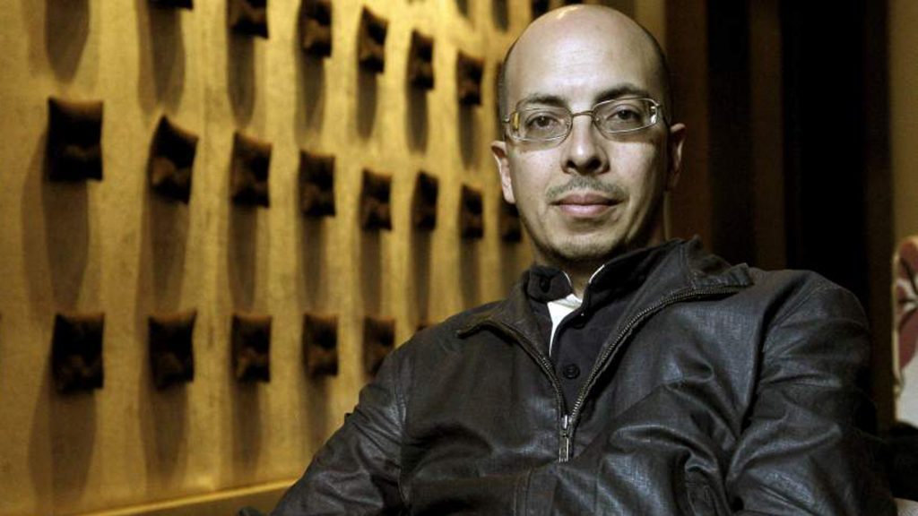 Jorge Volpi, escritor mexicano con gafas y chaqueta negra, retratado en ambiente nocturno con iluminación cálida