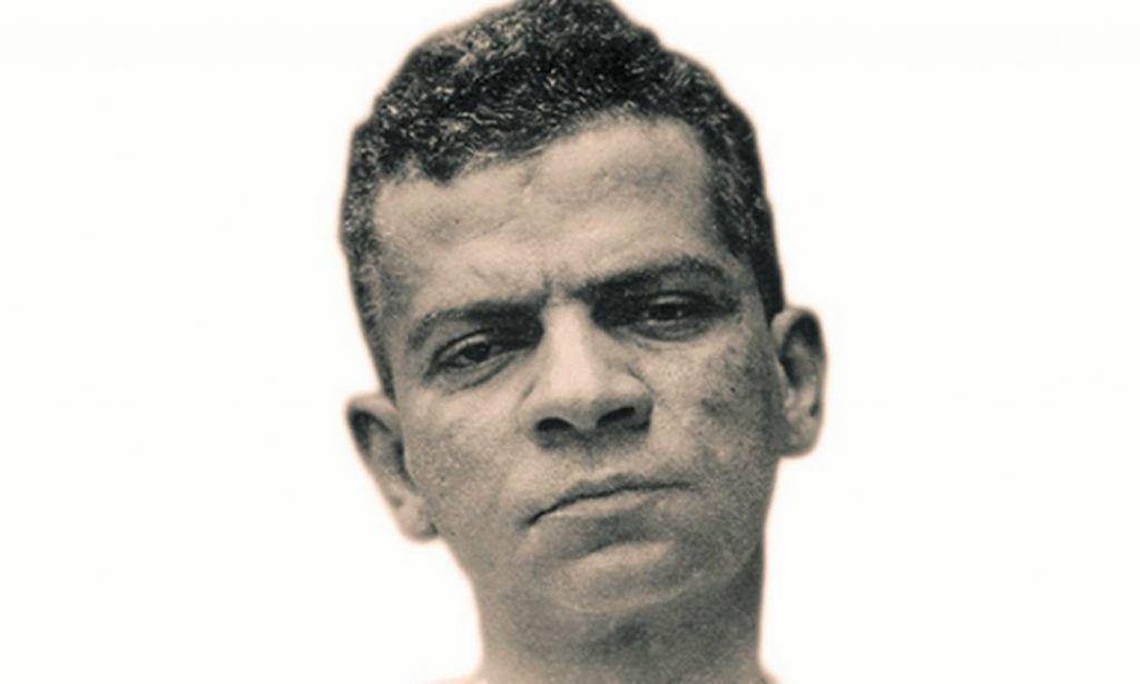 Retrato en blanco y negro del escritor brasileño Lima Barreto, mirando directamente a la cámara con expresión seria