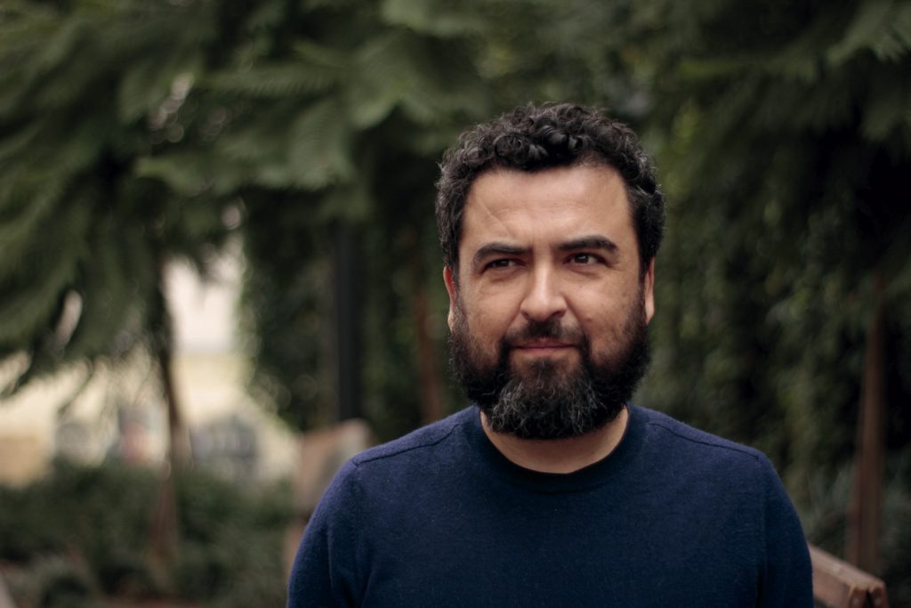 Óscar Contardo, sociólogo y escritor chileno, retratado en primer plano con fondo de vegetación
