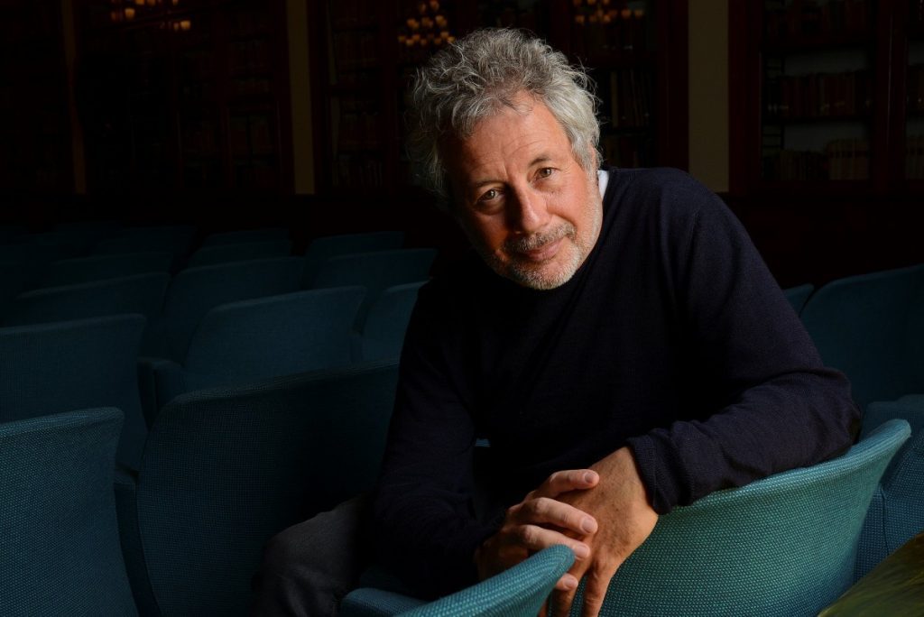 Escritor italiano Alessandro Baricco recostado en sillón azul, mirando hacia cámara con expresión reflexiva