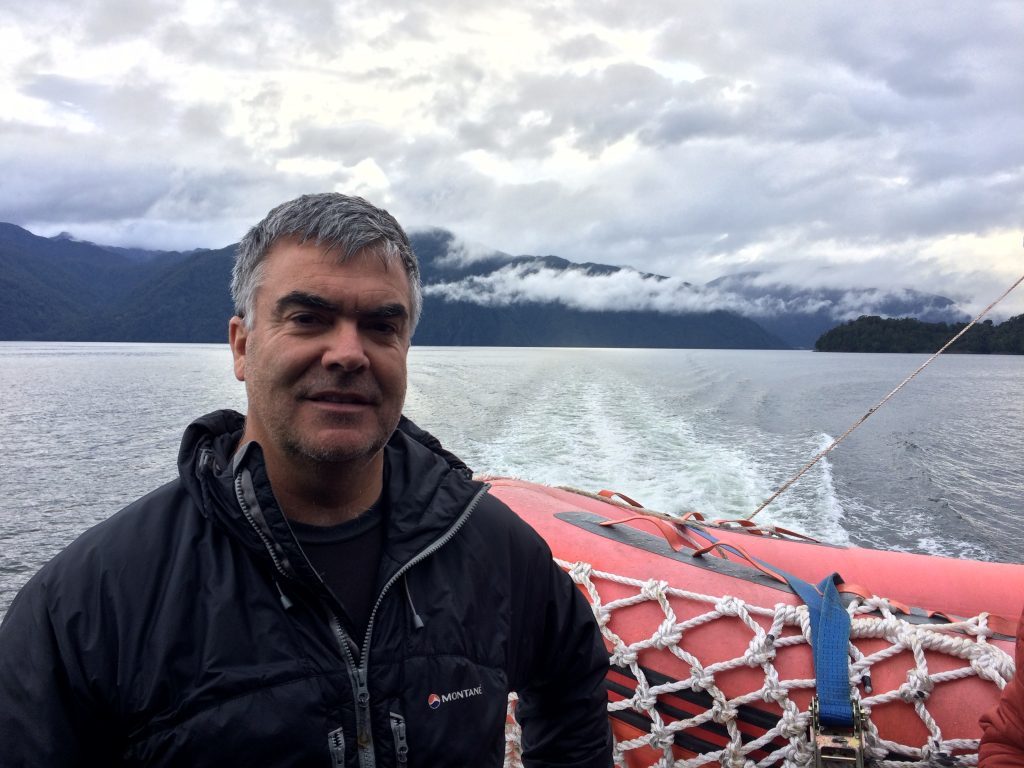 Rodrigo Barra Villalón en bote sobre lago con montañas nevadas de fondo