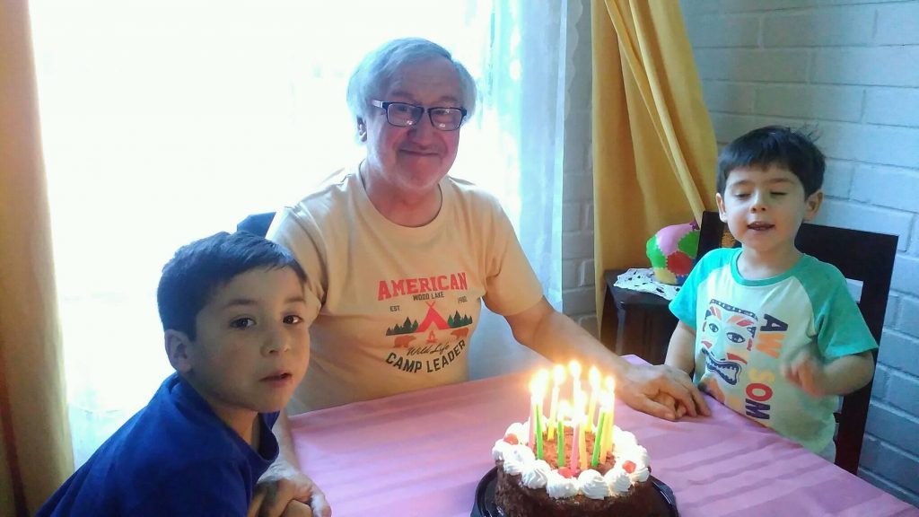 Gregorio Angelcos sopla velas de cumpleaños rodeado de dos niños en una habitación con decoración de globos