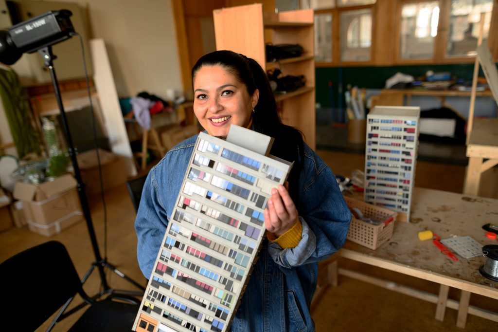 Cecilia Toro sostiene DVDs de sus películas en su estudio, rodeada de materiales de producción audiovisual