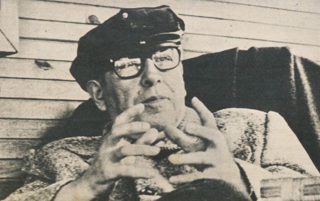 Poeta Pablo de Rokha con gafas y gorra, manos entrelazadas, expresión seria, fotografía en blanco y negro