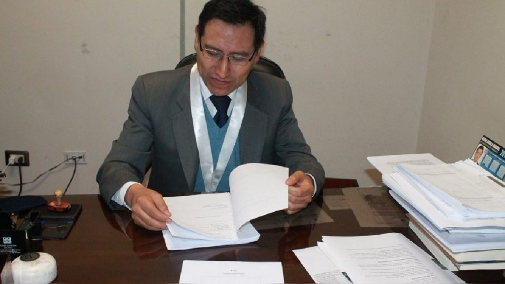 Jaime Coaguila Valdivia, juez peruano, revisa documentos en su escritorio de oficina con papeles y materiales de trabajo