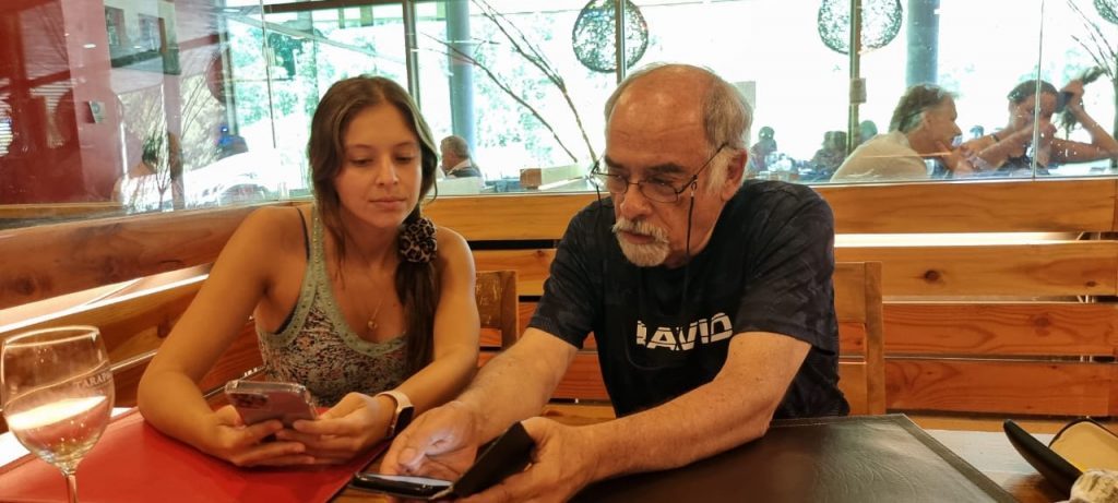 Juan Mihovilovich en conversación con una mujer durante una entrevista, ambos en un interior de madera clara