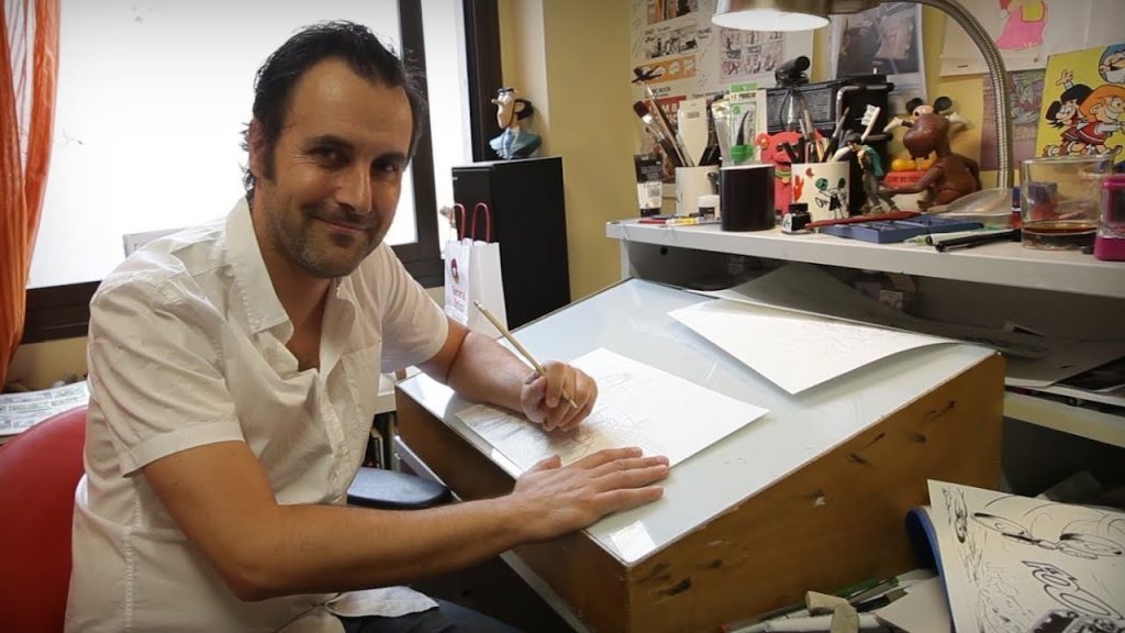 José Luis Munuera trabajando en su escritorio con papeles y materiales de dibujo