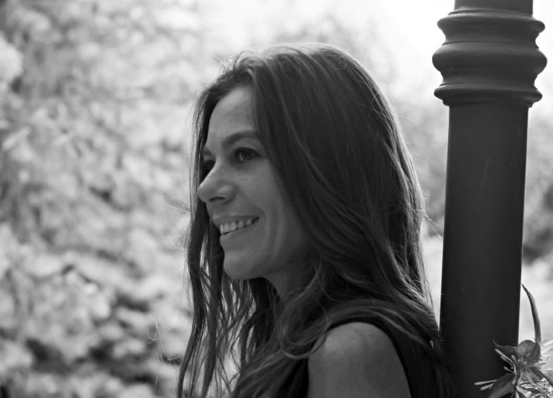 Mariana Travacio sonríe de perfil en blanco y negro, con columna arquitectónica de fondo