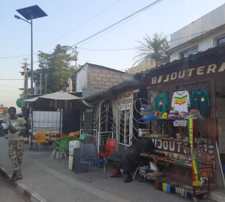 Tienda de películas y literatura en Cabo Skirring, Senegal, con fachada decorada y mercancía expuesta en la calle