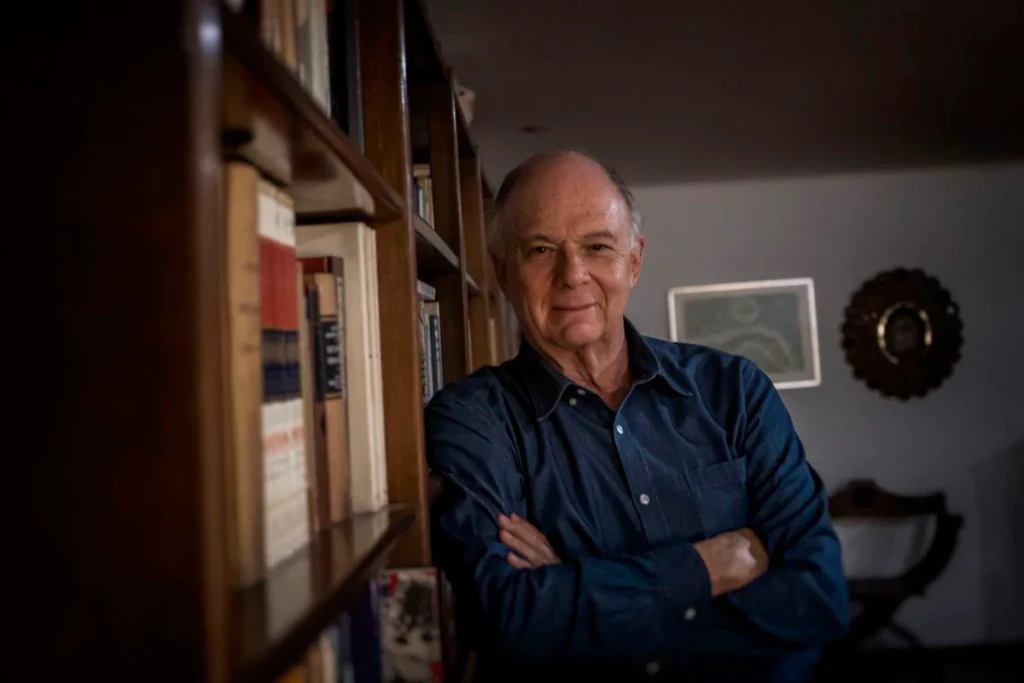 Enrique Krauze, historiador y escritor mexicano, de brazos cruzados frente a estantería con libros en su estudio