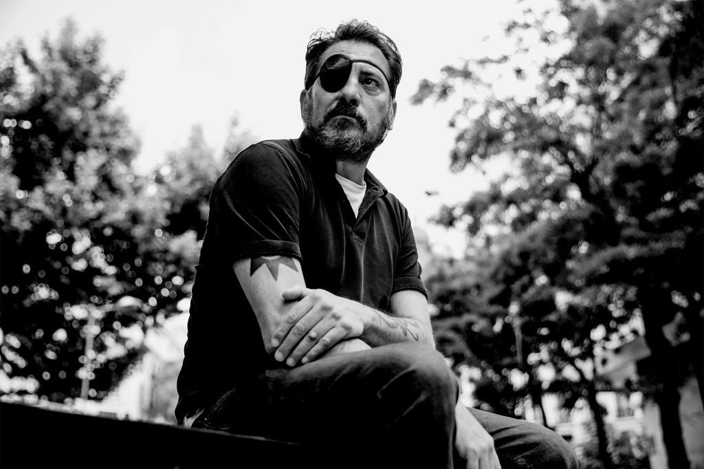 Retrato en blanco y negro de Ray Loriga, escritor español, sentado en la naturaleza con expresión contemplativa