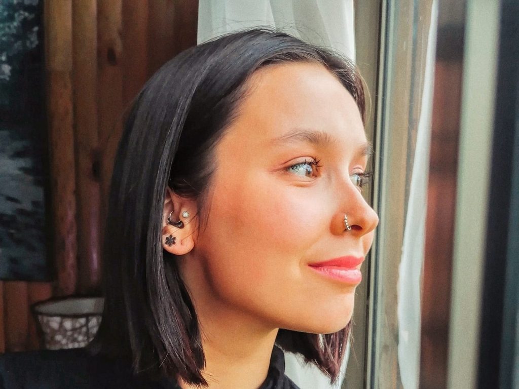 Sofía Cruz Villalobos, mujer de perfil, cabello negro liso, labios rosas, fondo desenfocado con tonos cálidos