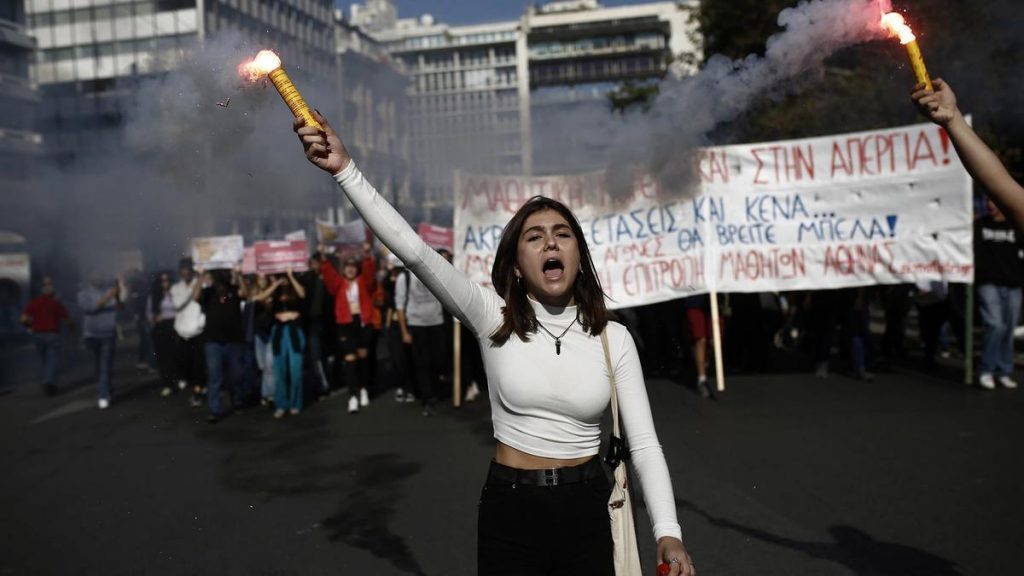 Mujer levanta el puño en manifestación urbana con carteles de protesta social de fondo y humo