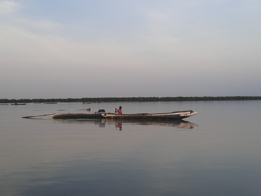 Barca de madera roja anclada en aguas tranquilas del río Casamance bajo cielo nublado, Ziguinchor