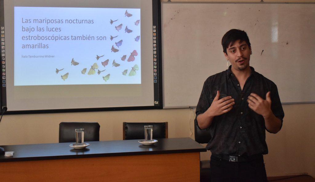 Ítalo Tamburrino Widner durante presentación sobre conservación in situ, con diapositiva proyectada al fondo en aula