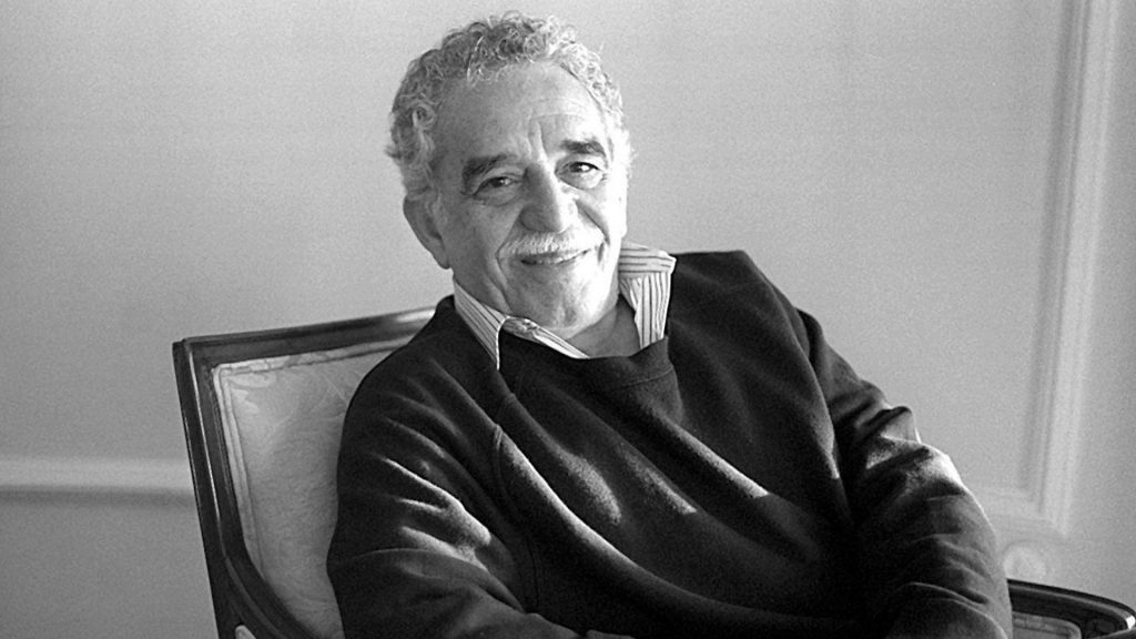 Gabriel García Márquez en retrato de estudio, sentado y sonriendo, fotografía en blanco y negro