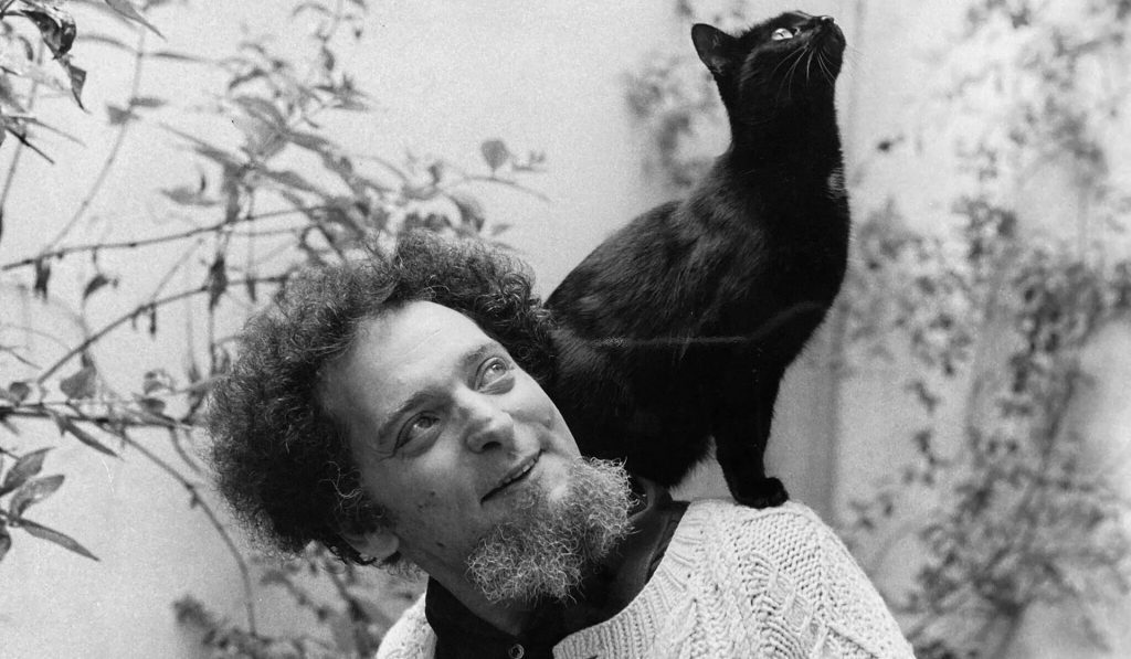 Georges Perec, escritor francés, con un gato negro sobre su hombro en fotografía en blanco y negro