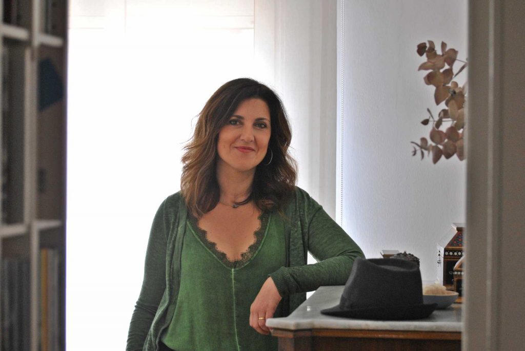 Mireia Rosich, mujer de cabello oscuro ondulado, viste cardigan verde y posa junto a una máquina de escribir negra