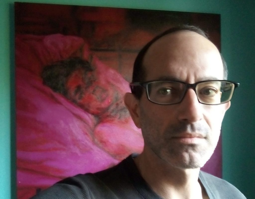 Nicolás Poblete Pardo, hombre de lentes y cabeza calva, frente a obra de arte abstracta en tonos rosa y magenta