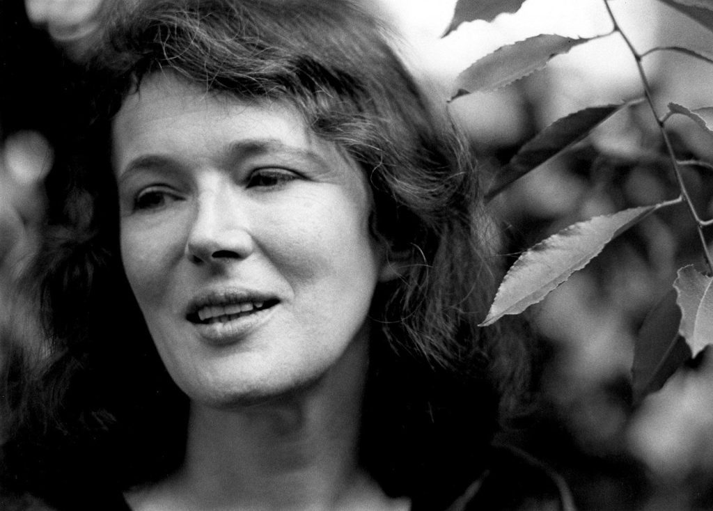 Retrato en blanco y negro de Angela Carter, escritora británica, con cabello largo y expresión serena ante fondo