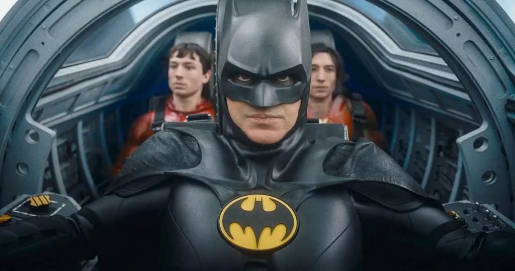 Batman en traje negro con emblema amarillo, flanqueado por dos figuras en rojo dentro de una nave futurista