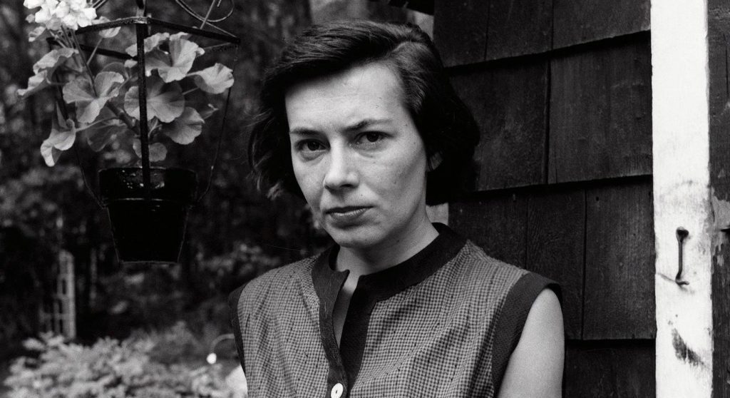 Patricia Highsmith, escritora estadounidense, retrato en blanco y negro en jardín, expresión seria y contemplativa