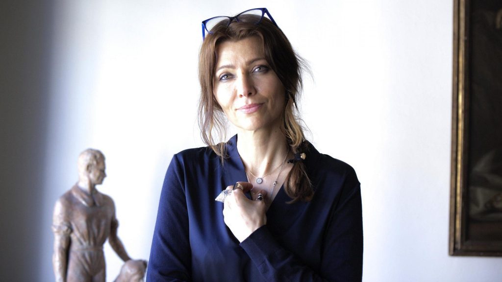 Elif Shafak, escritora turca, con gafas en la cabeza y expresión reflexiva en interior blanco