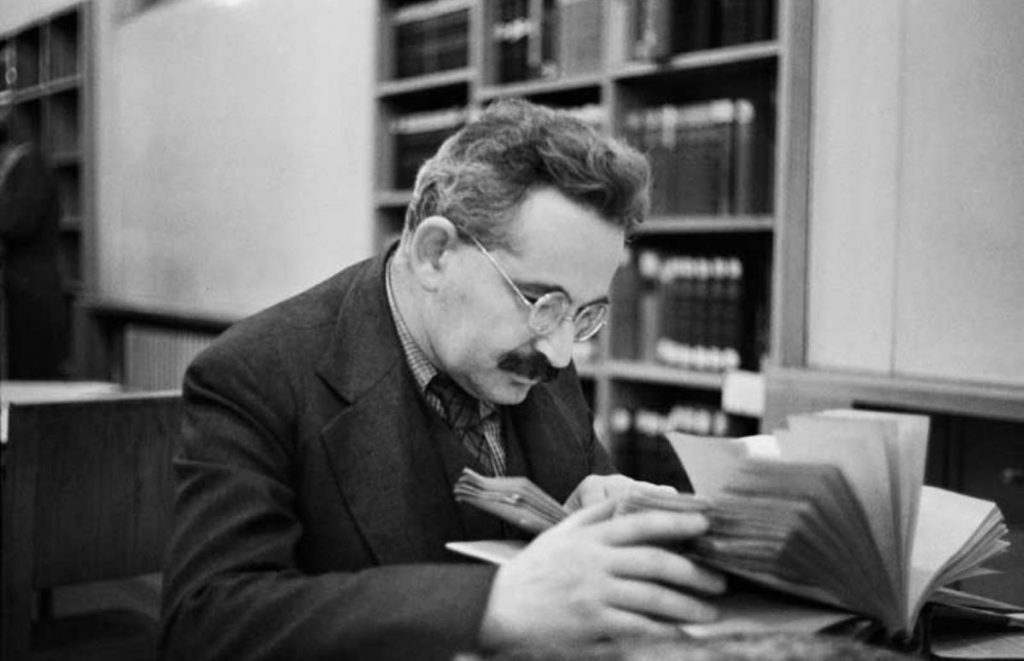Walter Benjamin con gafas leyendo un libro en una biblioteca, fotografía en blanco y negro